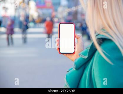 Foto in primo piano delle mani femminili che tengono uno smartphone moderno con schermo vuoto. Mockup pronto per messaggi di testo o contenuti. Le mani della donna con il cellulare. EMP Foto Stock