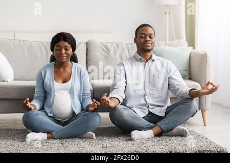 Rilassato aspettandosi una coppia nera che pratica yoga insieme Foto Stock
