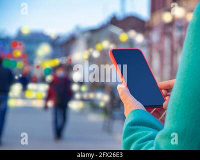 Foto in primo piano delle mani femminili che tengono uno smartphone moderno con schermo vuoto. Mockup pronto per messaggi di testo o contenuti. Le mani della donna con il cellulare. EMP Foto Stock