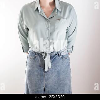Ragazza alla moda in blusa con lacci sul fondo e gonna in denim su sfondo bianco. Concetto di donna di affari e di shopping Foto Stock