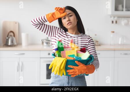 Donna asiatica che lavora sodo con busket pieno di forniture per la pulizia Foto Stock