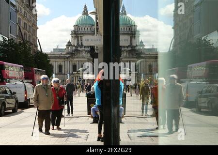 Belfast 25 maggio 2021. La gente esce dai negozi nel centro di Belfast mentre i negozi e gli affari riaprono dalla chiusura di Covid. La gente dell'Irlanda del Nord è ora in grado di gustare un drink o un boccone da mangiare all'interno di pub e ristoranti, poiché l'ospitalità apre completamente per la prima volta da dicembre. Sei persone provenienti da un numero qualsiasi di famiglie possono sedere insieme o fino a 10 persone, a condizione che siano tutte della stessa famiglia. L'allentamento delle restrizioni del coronavirus significa anche che sei persone provenienti da due famiglie possono ora incontrarsi in casa. Credit: Paul McErlane/Alamy Live News Foto Stock