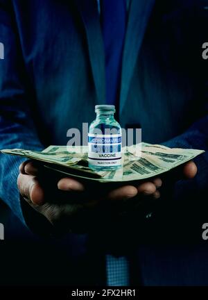 primo piano di un giovane uomo d'affari caucasico con un covid-19 simulato bottiglia di vaccino e un mazzo di banconote in dollari nel suo mani Foto Stock