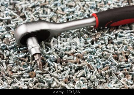 Cacciavite poggiato su una pila di viti. Attrezzo e attrezzatura. Primo piano Foto Stock