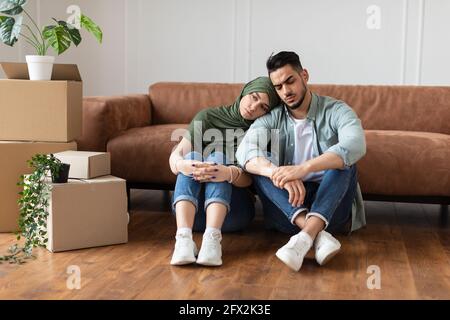 Famiglia stanca seduta sul pavimento con scatole di cartone Foto Stock