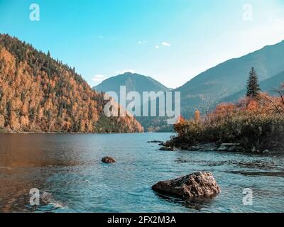 Vista panoramica di un lago di montagna sullo sfondo di montagne su un cielo azzurro limpido e senza nuvole, paesaggio di montagna. Foto Stock