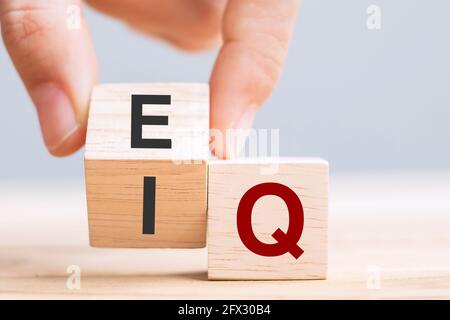 Business uomo mano cambiare legno cubo blocco da IQ a EQ, equilibrio tra intelligenza quoziente e concetti di intelligenza emotiva Foto Stock