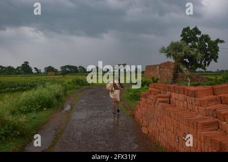 Hoogly, India. 25 Maggio 2021. Un uomo visto camminare sotto la pioggia prima della caduta del ciclone 'Yaas' nel Bengala occidentale.Cyclone 'Yaas' probabilmente farà la caduta tra Balasore e Digha Coastal zone il 26 maggio, Mercoledì mattina. Come tempesta ciclonica molto grave, può causare forti precipitazioni nei distretti costieri del Bengala Occidentale e del Nord Odisha. Credit: SOPA Images Limited/Alamy Live News Foto Stock