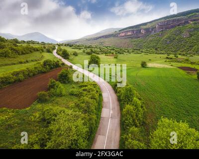 Vista aerea del drone della strada asfaltata e dei prati con verde Erba in primavera. Natura destinazione di viaggio all'aperto, Stara Planina (montagna balcanica), Serbia Foto Stock