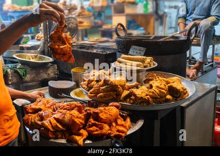 Pollo torrefatto piccante tandoori, kabab di pollo, preparato per la vendita alla sera come cibo di strada nel mercato di Old Delhi. E' famoso per gli Indiani piccanti non vegetariani Foto Stock