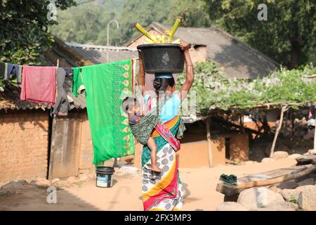 TRIBÙ LANJIA SAORA. Donna tribale che va al mercato del villaggio con il suo bambino che è legato dal suo sari pallu sulla schiena. Riginghtal villaggio, Odisha, India Foto Stock