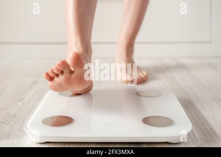 Il piede della donna fa un passo su una scala intelligente che fa l'analisi bioelettrica dell'impedenza, BIA, misure del grasso corporeo. Foto Stock