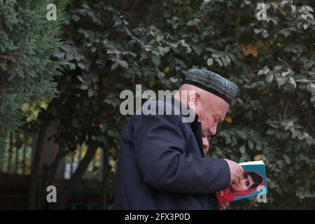 Uighur vecchio che legge fuori della Moschea Id Kah .Kashgar, Xingiang, Cina 2019 Foto Stock
