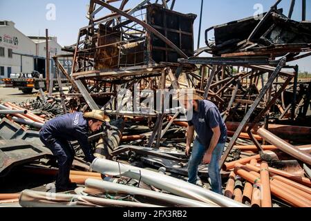 Gaza, Palestina. 25 Maggio 2021. Un lavoratore palestinese salva gli oggetti in una fabbrica di tubi di plastica danneggiata nella zona industriale di Gaza, dopo gli scioperi israeliani. Il diplomatico statunitense Antony Blinken ha promesso sostegno per contribuire alla ricostruzione della striscia di Gaza martoriata e per costellare una tregua tra Hamas e Israele, Ma insisteva che i governanti militanti islamisti del territorio non avrebbero beneficiato di alcun aiuto. Credit: SOPA Images Limited/Alamy Live News Foto Stock