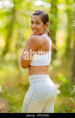 Donna atletica sorridente in Sportswear contro gli alberi Foto Stock