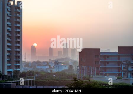 dawn shot di grattacieli e piccole case sullo sfondo con edifici alti con uffici case nascosti dalla nebbia dentro lo sfondo con il sole che sorge Foto Stock