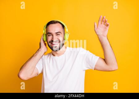 Ritratto di ottimista ragazzo ascoltare musica danza indossare t-shirt grigio isolato su uno sfondo di colore giallo vivace Foto Stock