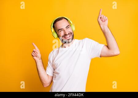 Ritratto di ottimista funky ragazzo ascoltare musica danza indossare grigio t-shirt isolata su sfondo giallo brillante Foto Stock