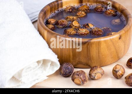 Rosolare le saponette secche (Soapbaces, Sapindus Mukorossi) in acqua con l'asciugamano per la lavanderia biologica e la cura delicata della pelle naturale su sfondo chiaro Foto Stock