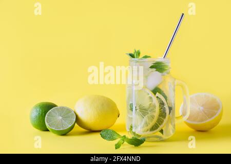 Limonata estiva fresca con limone, lime, arancia e menta su sfondo giallo. Primo piano. Spazio di copia. Foto Stock