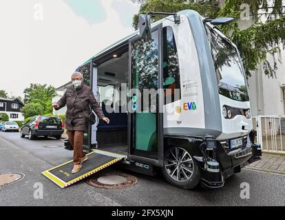 Karlsruhe, Germania. 17 maggio 2021. Sieglinde Vater esce da un minibus autonomo dopo aver fatto un viaggio attraverso un quartiere di Karlsruhe. Ciò faceva parte del progetto di ricerca 'EVA Shuttle'. In questo progetto, i minibus che guidano autonomamente e che non emettono emissioni trasportano i loro passeggeri da A a B nel distretto, a seconda delle necessità. L'ordine viene effettuato tramite l'app. I veicoli si muovono liberamente nel traffico stradale regolare, che, secondo l'operatore, è unico in Germania in questa costellazione. Credit: Uli Deck/dpa/Alamy Live News Foto Stock