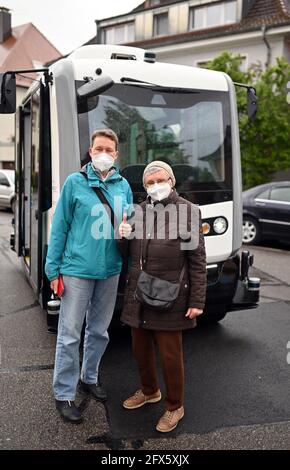 Karlsruhe, Germania. 17 maggio 2021. Sieglinde Vater (r) si erge con la figlia Gudrun di fronte a un minibus autonomo. In precedenza avevano preso l'autobus in un viaggio attraverso un quartiere di Karlsruhe. Faceva parte del progetto di ricerca 'EVA Shuttle'. In questo progetto, i minibus che guidano autonomamente e che non emettono emissioni trasportano i loro passeggeri da A a B nel distretto, a seconda delle necessità. L'ordine viene effettuato tramite l'app. I veicoli si muovono liberamente nel traffico stradale regolare, che, secondo l'operatore, è unico in Germania in questa costellazione. Credit: Uli Deck/dpa/Alamy Live News Foto Stock