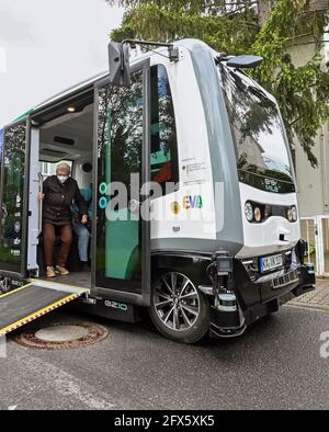 Karlsruhe, Germania. 17 maggio 2021. Sieglinde Vater esce da un minibus autonomo dopo aver fatto un viaggio attraverso un quartiere di Karlsruhe. Ciò faceva parte del progetto di ricerca 'EVA Shuttle'. In questo progetto, i minibus che guidano autonomamente e che non emettono emissioni trasportano i loro passeggeri da A a B nel distretto, a seconda delle necessità. L'ordine viene effettuato tramite l'app. I veicoli si muovono liberamente nel traffico stradale regolare, che, secondo l'operatore, è unico in Germania in questa costellazione. Credit: Uli Deck/dpa/Alamy Live News Foto Stock