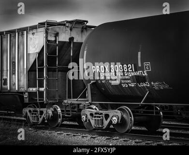 Un'immagine in bianco e nero di due treni parziali: Un'auto a grano e un'auto a petrolio. Foto Stock