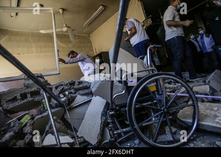 Gaza, la striscia di Gaza, la Palestina. 23 maggio 2021. I palestinesi guardano alle macerie di un centro sanitario distrutto dopo il cessate il fuoco tra Israele e i militanti di Gaza nella striscia di Gaza. Il primo diplomatico statunitense Antony Blinken ha promesso sostegno per contribuire alla ricostruzione della striscia di Gaza martoriata e per costeggiare una tregua tra Hamas e Israele, Ma insisteva che i governanti militanti islamisti del territorio non avrebbero beneficiato di alcun aiuto. Credit: Mahmoud Issa/SOPA Images/ZUMA Wire/Alamy Live News Foto Stock