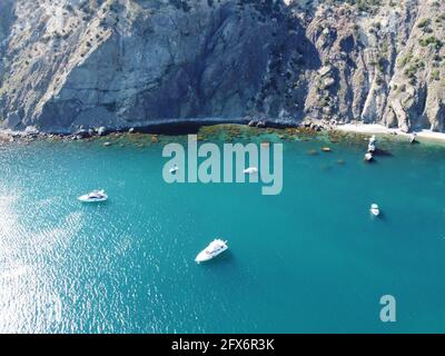 Vista aerea dall'alto sul mare azzurro e sulle coste rocciose. Piccole onde sulla superficie cristallina dell'acqua sfocata. Natura estate mare mare spiaggia Foto Stock