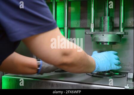 Stabilimento di produzione dell'acciaio. Un lavoratore sta posizionando un pezzo di metallo all'interno della stampa. La stampante viene premuta verso il basso. Metallurgia. Processo di produzione. Primo piano. Foto di alta qualità. Foto Stock