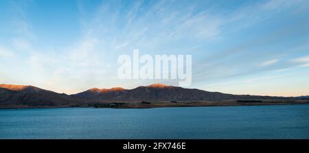 Lago Tekapo al tramonto. Tramonto illuminato in cima alle montagne. Isola Sud Foto Stock