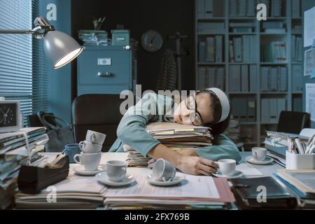 Lavoratore esausto che si addormenta in ufficio tardi a. la notte dopo aver bevuto troppo caffè Foto Stock