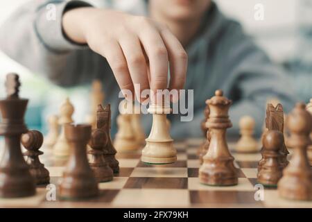 Ragazzo che gioca a scacchi e muove un pezzo, mano da vicino Foto Stock