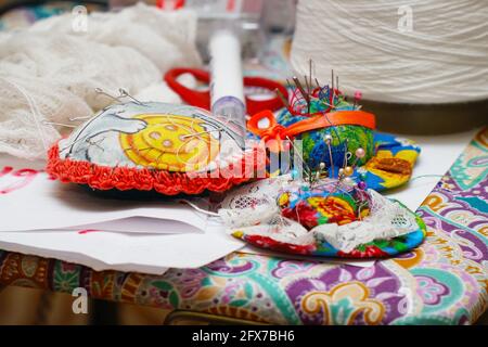 Aghi da cucire su un cuscino, fili e accessori per l'ago. Messa a fuoco selettiva Foto Stock