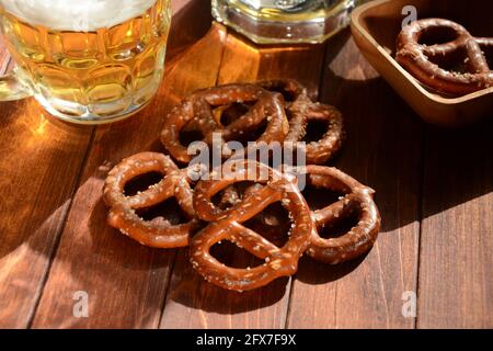 Pretzel duri o uno spuntino di pretzel salati per una festa in stile rustico tavolo in legno con bicchiere di birra Foto Stock