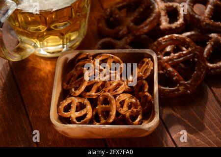 Pretzel duri o uno spuntino di pretzel salati per una festa in stile rustico tavolo in legno con bicchiere di birra Foto Stock