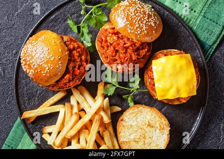 Panini fatti in casa al barbecue Sloppy Joe con patatine fritte su un piatto nero, piatto, primo piano, cucina americana Foto Stock