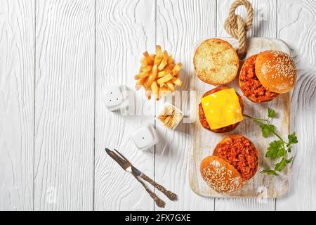 Panini Slippy Joe su brioche panini serviti con patatine fritte su un bordo di legno bianco, primo piano, cucina americana Foto Stock