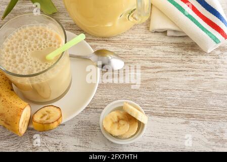 colazione sana con dettaglio di agitare il latte di banana in contenitori su tavola di legno e frutta tagliata. Vista dall'alto. Foto Stock