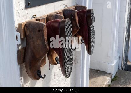 Le vecchie scarpe di legno si trasformano in un espositore all'esterno di un negozio di riparazione scarpe, High Street, Stony Stratford, UK Foto Stock