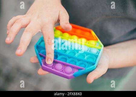 Schiocchili il giocattolo del fidget in mano della ragazza. Colorato antistress bambino giocattolo fidget. Foto Stock