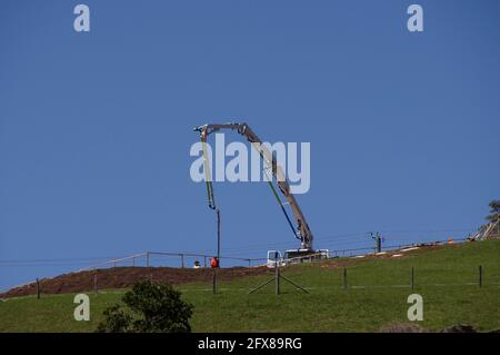 Pompa per calcestruzzo, montata su camion, che getta le basi per una nuova casa in un sito rurale in cima alla collina, Queensland, Australia. Spazio di copia. Foto Stock