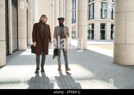 Due giovani amici che parlano e camminano all'aperto in città Foto Stock