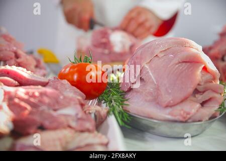 Colpo di closeup di un macellaio contenente carne tagliata di fresco con verdure Foto Stock