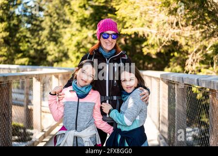 Ritratto di famiglia che visita la passerella di osservazione in legno sulla cima degli alberi in inverno. Famiglia con bambini sopra le cime degli alberi sul ponte pedonale in legno del balcone Foto Stock