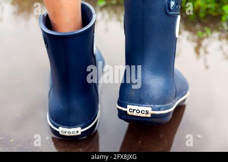 Tambov, Federazione Russa - 08 agosto 2019 gambe in blu stivali Crocs nel puddle. Primo piano Foto Stock