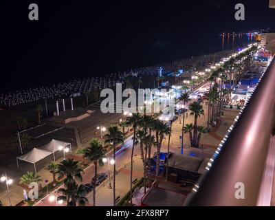 Vista aerea superiore con vista notturna sul lungomare delle palme Finikoudes, strada con luci auto, ombrelloni vicino al mare Mediterraneo e orizzonte. Foto Stock