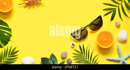 Sfondo estivo. Foglia di palma, arancio, stelle marine e conchiglia su sfondo giallo. Viaggi. Spazio di copia. Foto Stock