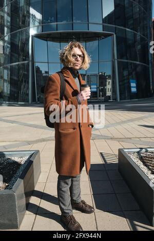 Giovane uomo che beve caffè mentre si trova sulla strada all'aperto Foto Stock